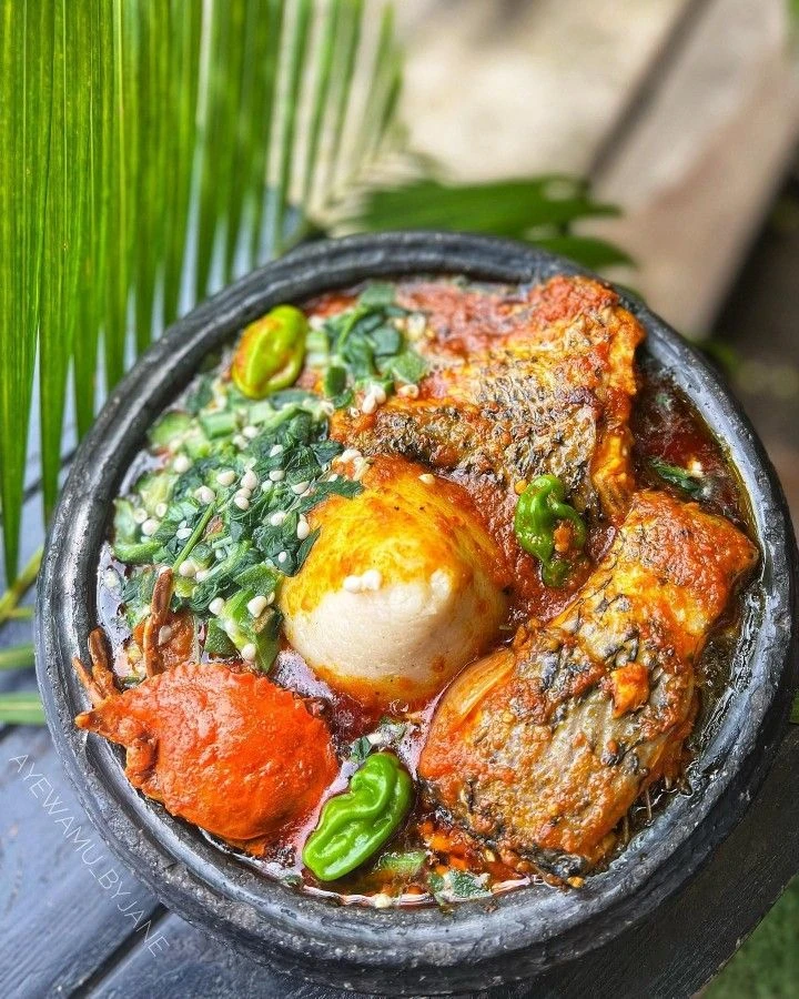 Fish and okra soup with leafy greens in a dark bowl
